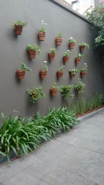 Çit oldukça kasvetli görünüyor ama terracotta saksılardaki çiçekler ve otlar mekana canlılık katıyor.