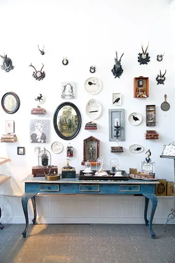 Tabaklar, sanat eserleri ve yapma hayvan derileriyle oluşturulmuş vintage tarzda galeri duvarı.