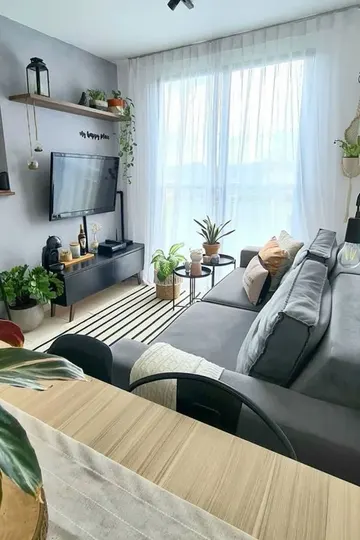 Duvara monte TV ve tüm kablolar siyah kablo kanallarına gizlenmiş şık küçük bir İskandinav salonu.