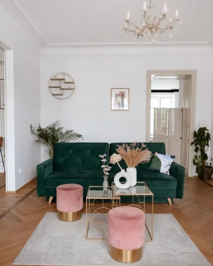 Beyaz oda, koyu yeşil kanepe ve pembe puflarla, parlak altın dokunuşlarıyla glam bir görünüm kazanıyor.