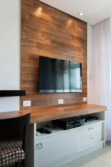 TV'yi vurgulayan ve kabloları saklayan ahşap sahte duvar, mekâna sıcak ve rustik bir hava katıyor.