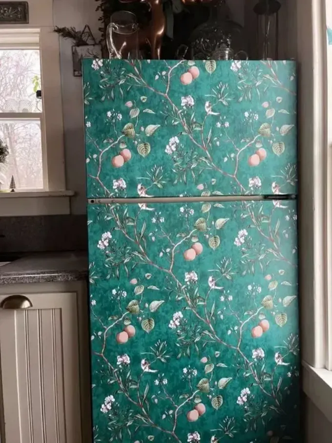 Buzdolabı, alana yaratıcı ve renkli bir dokunuş katmak için yeşil duvar kağıdı ile kaplanmış.