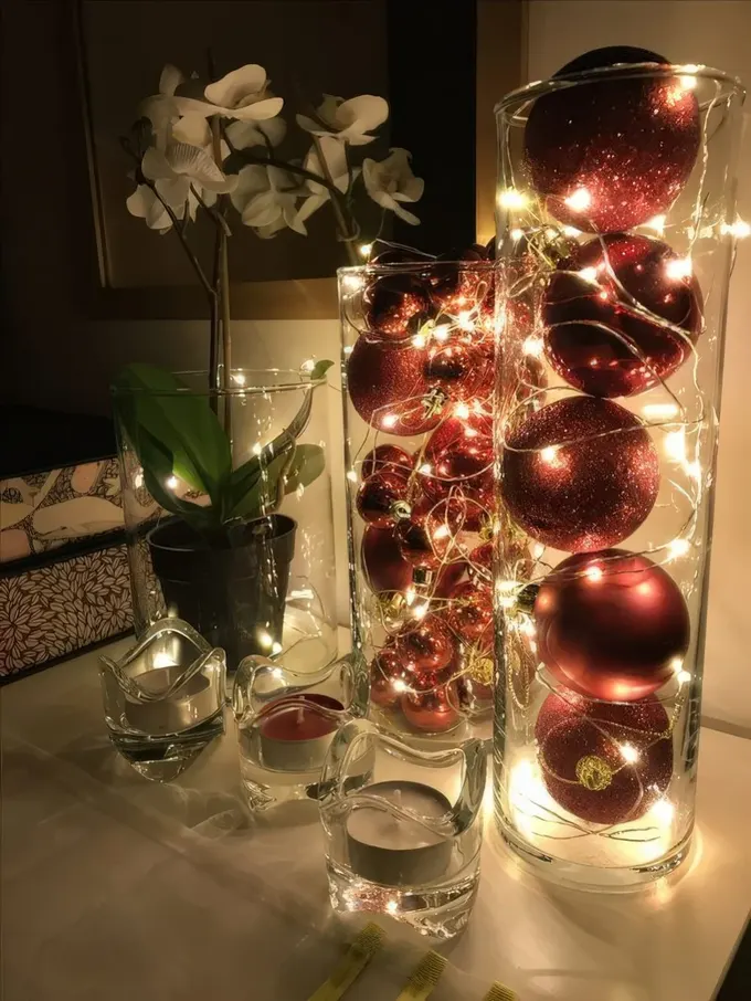 Kırmızı ve kırmızı simli süsler ile ışıklarla dolu uzun cam vazolar muhteşem tatil dekoru.