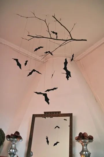 Tavandan asılan siyah bir dal ve asılı yarasalarla kolayca yapabileceğiniz basit bir Halloween dekoru.