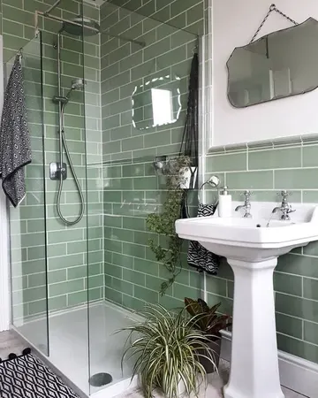 Yeşil metro karolarla kaplı küçük banyo, duş, bağımsız lavabo ve dikkat çekici aynasıyla.