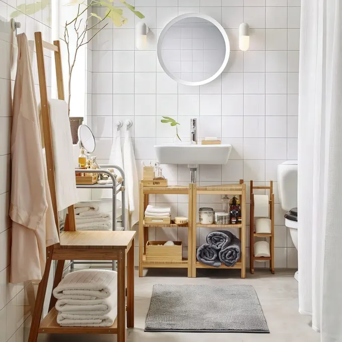 Nötr renklerde modern, sade mobilyalı banyo; havlular lavabo dolabı ve taburenin içinde.