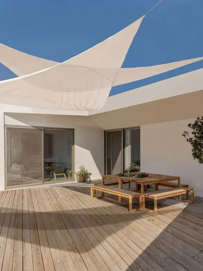 Minimalist güvertede, estetiğe uyumlu birkaç beyaz gölge bezi bulunuyor.