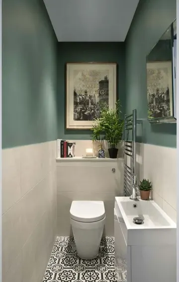 Yeşil ve beyaz fayanslı duvarları, depolama için lavabo ve birkaç sanat eseriyle şık küçük misafir tuvaleti.