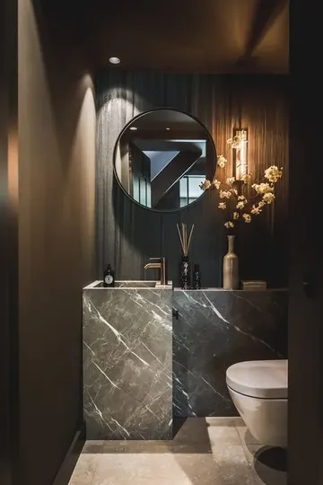 Taş lavabo ve dolap, ayna, taş duvar ve canlı çiçeklerle lüks ve modern misafir tuvaleti.