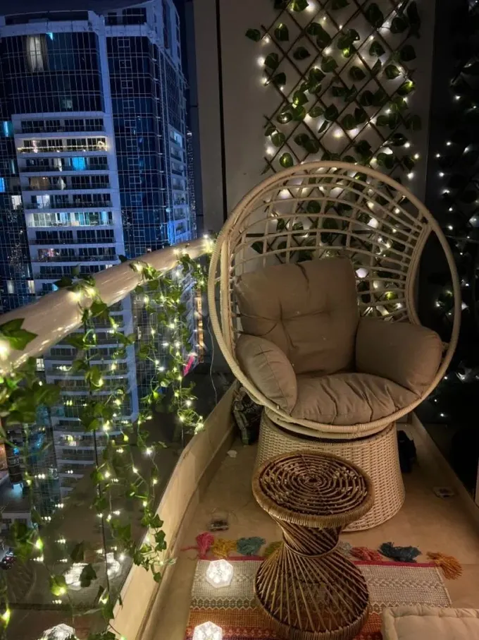 Modern alan, rattan parçalarla döşenmiş, ip ışıklar yaprak süsü dizileriyle birlikte aydınlatıyor.