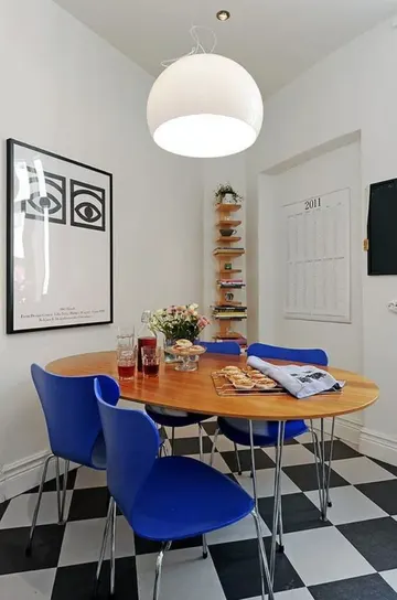 Şık modern yemek alanı lekeli masa, kitaplık ve kobalt mavi sandalyeleri gösteriyor.