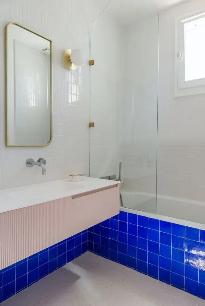 Nötr banyo renklendirilmiş: kobalt mavi fayanslar, pembe lavabo ve altın aksanlarla eşleştirilmiş.