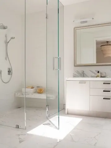 Mermer zeminli, uyumlu asma oturaklı ve kesintisiz cam kapılı hayali gibi duş alanı.