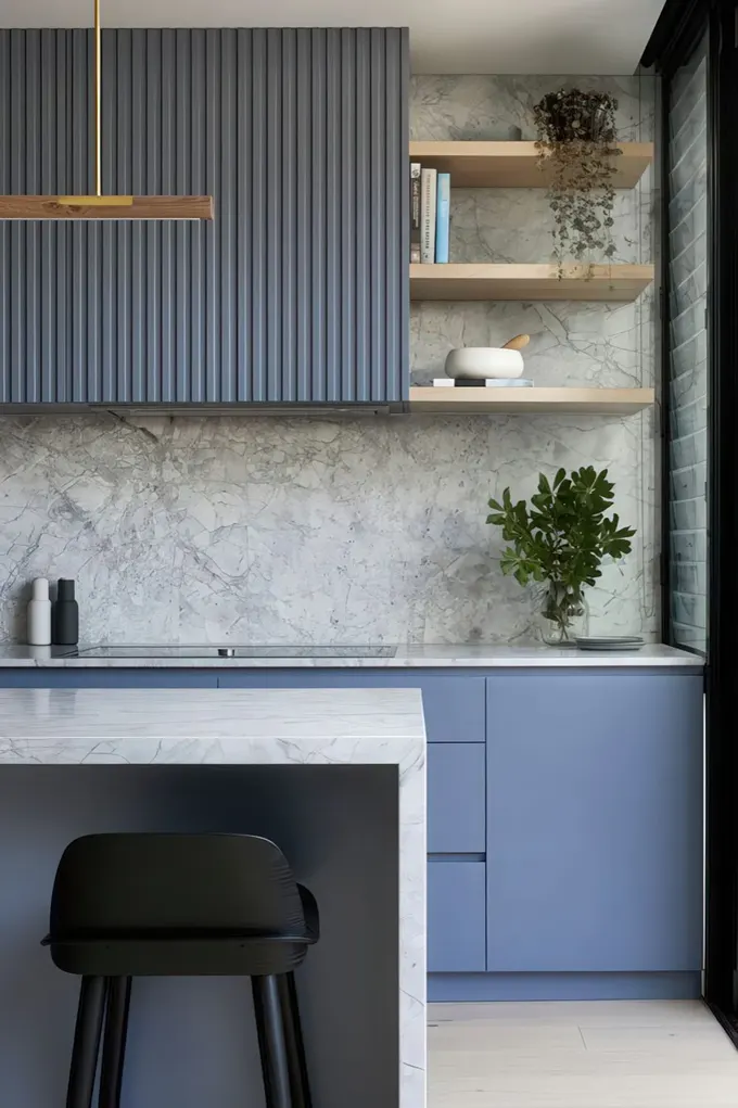 Gri taş sırtlık ve tezgahlar, saksı yeşillikleri ve altın dokunuşlarıyla minimalist mavi mutfak.