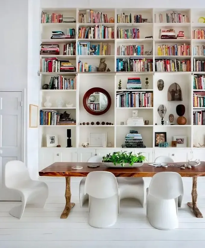 Çift katlı kitaplıklarda kitapların yanı sıra dekor ve sanat eserleri sergileniyor. Yemek bölümü modern ve eskiyi birleştiriyor; vintage masa beyaz kıvrımlı sandalyelerle eşleşiyor.