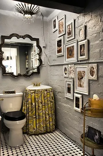 Boyalı tuğla duvarlar, vintage çerçeveli ayna, galeri duvarı ve kumaş perdeyle kaplanmış lavabo bulunan eklektik banyo.