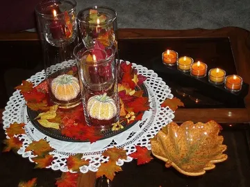 Mumlar, yapay yapraklar, yapay balkabakları ve yaprak kaseleriyle sade sonbahar kahve masası.