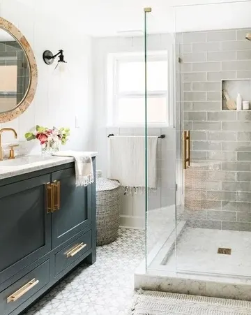 Gri ve desenli yer karoları, grafit gri lavabo ve tek kumandalı cam kapılı duş alanı olan küçük banyo.