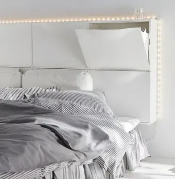 Altı beyaz IKEA TRONES ayakkabılık, duvara monte depolamalı başlık ve ekstra ışıklar yaratmak için yeniden kullanıldı. Küçük alanlarda düzen ve şıklık sağlar.
