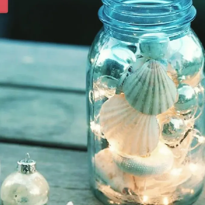 Bir kavanozda tarak kabukları ve ışıklarla dolu, masaya deniz havası ve sıcaklık katan büyüleyici bir parça.