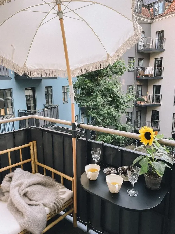 Balkon siyah asma masa, rattan kanepe ve şemsiye ile düzenlenmiş.