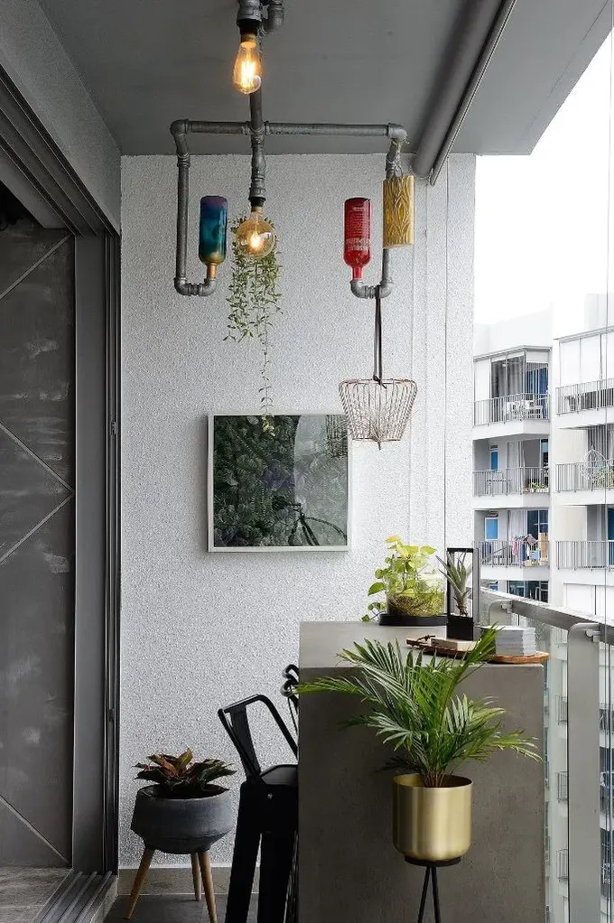 Balkon, beton masa, metal sandalye, lamba ve benzersiz boru avize ile dikkat çekici bir endüstriyel çalışma alanına çevrilmiş.
