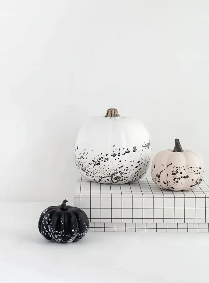 Beyaz, siyah ve pembe sıçratmalı minimal kabaklar göz alıcı bir minimalist Halloween dekoru sunuyor.