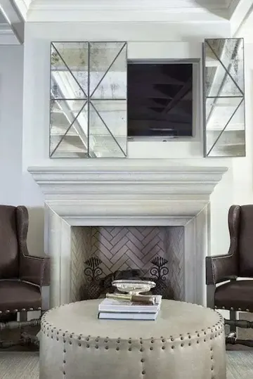 Tuğla kaplı şömine ve eski aynalı panellerle gizlenmiş TV, vintage nötr bir oturma odasında harika bir fikir.