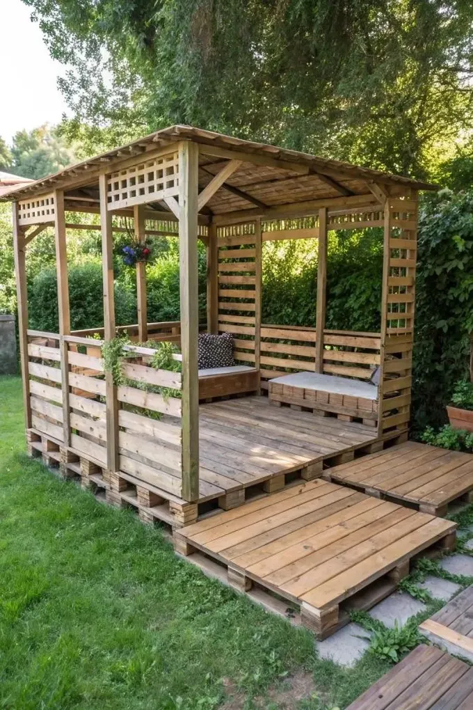 Palet pergola birkaç şezlong içeriyor ve sağlam çatısı yağmurdan koruma sağlıyor.