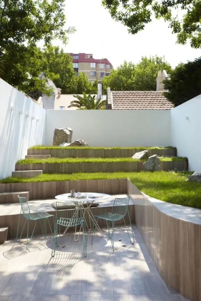 Bu küçük alan, çim ve taşlarla minimalist katlı bahçeye dönüştürülmüş.