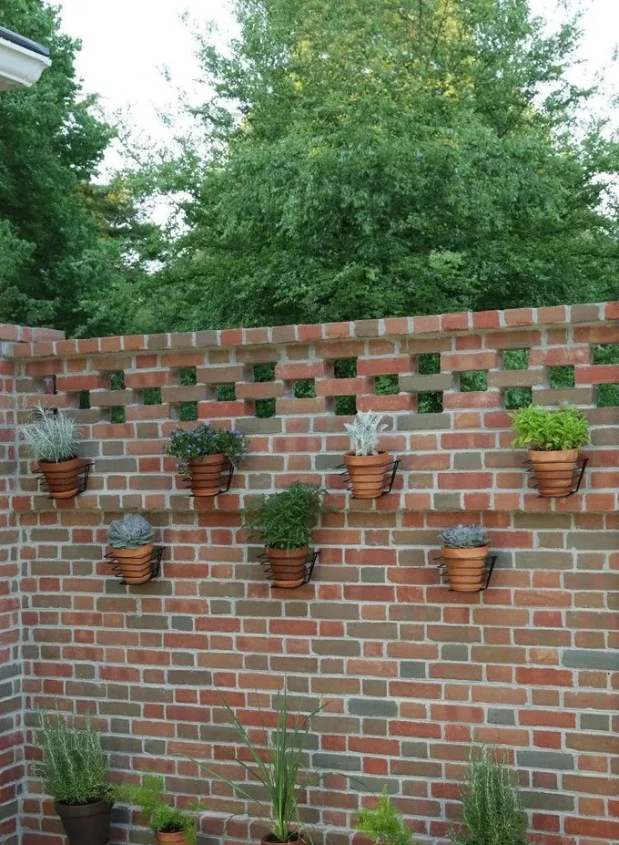 Tuğla çit oldukça rustik görünüyor, ancak yeşil yapraklı terracotta saksılar ona hayat veriyor.
