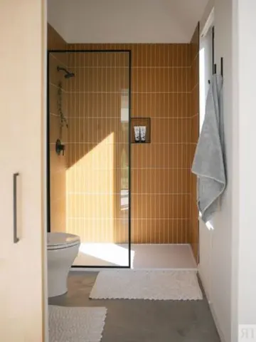 Sarı ince karolar kaplı duş alanı, beton zemin ve beyaz cihazlarla aydınlık küçük banyo.