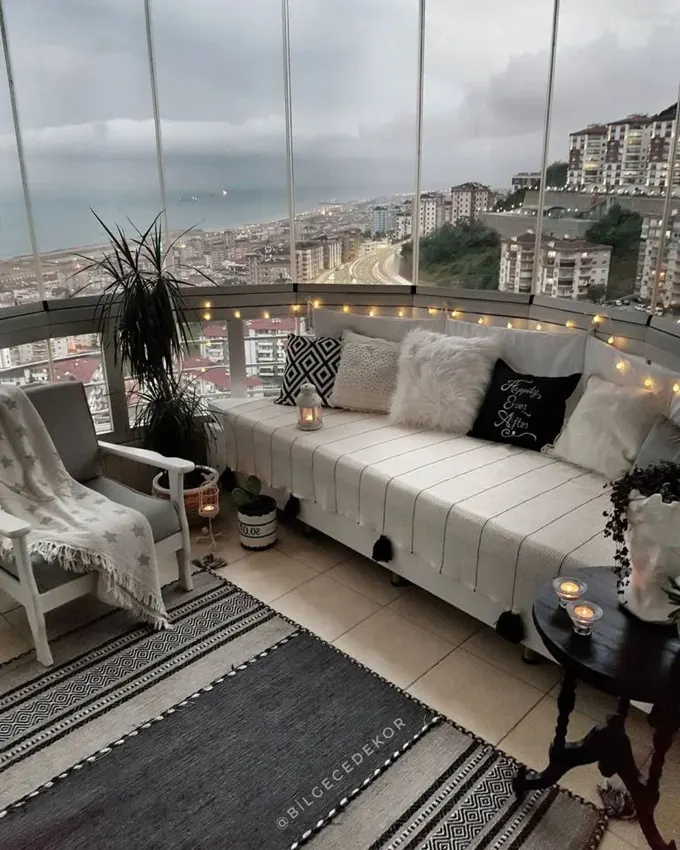 Kavisli balkon, şehir manzarası ve siyah-beyaz renk düzeniyle açık hava oturma odası gibi tasarlanmış.