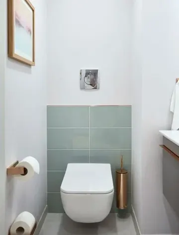 Aqua karolar, bakır detaylar ve lavabolu asma lavabo dolabı ile sade misafir tuvaleti.