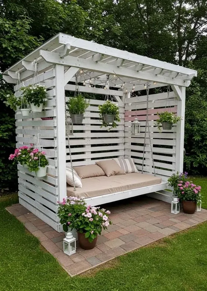 Şık beyaz pergola, sallanan gündelik ve üzerine asılan çok sayıda bitkiyle yapılmış.