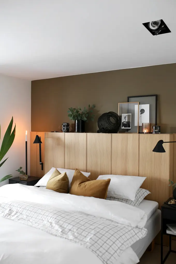 IKEA Ekestad meşe mutfak kapakları ve panellerle yapılmış depolamalı DIY başlık. Kitaplar için gömme depolama ve duvara monte okuma ışıklarıyla pratik.