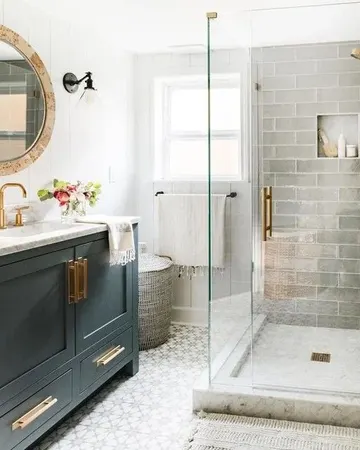 Gri uzun ve desenli fayanslı küçük banyo. Grafit gri lavabo, altın detaylar ve mermer tezgah bulunuyor.
