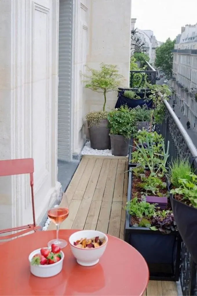 Uyumlu bitkiler ve uzun saksılarla şık bir balkon oluşturulmuş, turuncu metal mobilyalar ise oturmaya davet ediyor.