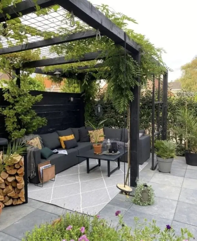 Siyah pergola birçok yeşillik ile kaplanmış, mekanı canlandıran hoş bir kafes örneği.