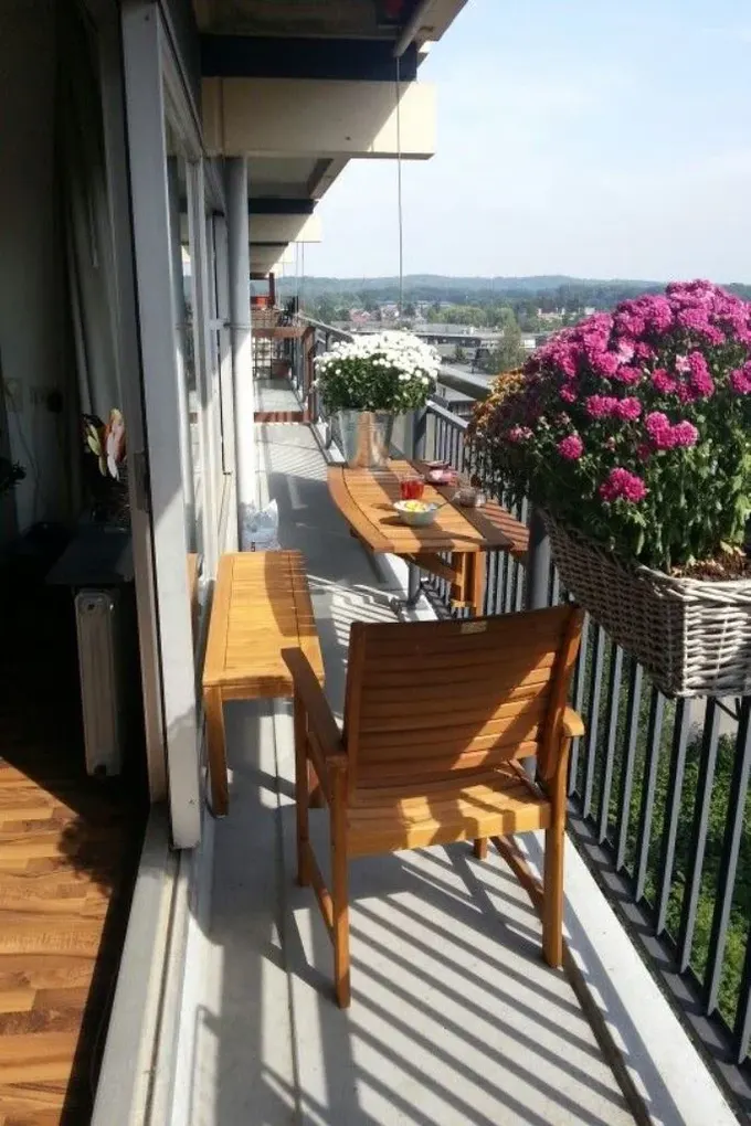 Dar balkon, korkuluğa monte masa, sandalye ve bank ile küçük bir yemek alanı sunuyor.