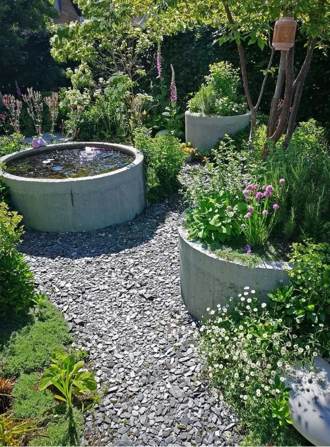 Yükseltilmiş beton bahçe yatakları bir göletle birlikte modern ve şık bir peyzaj oluşturuyor.