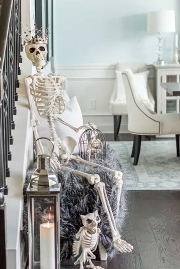 Taç takmış iskelet, kafeste iskelet kuş ve iskelet baykuşun yer aldığı şık ve eğlenceli Halloween sahnesi.