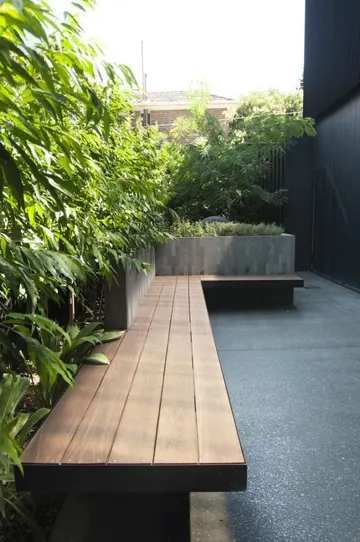 Bu dış mekan alanı yeşil duvar, bitki dolu saksı ve gömme oturma ile minimalist şekilde düzenlenmiştir.