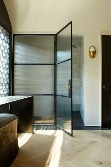Siyah mobilyalar ve siyah çerçeveli fitilli cam kapılı duş alanıyla tamamen şık bir banyo.