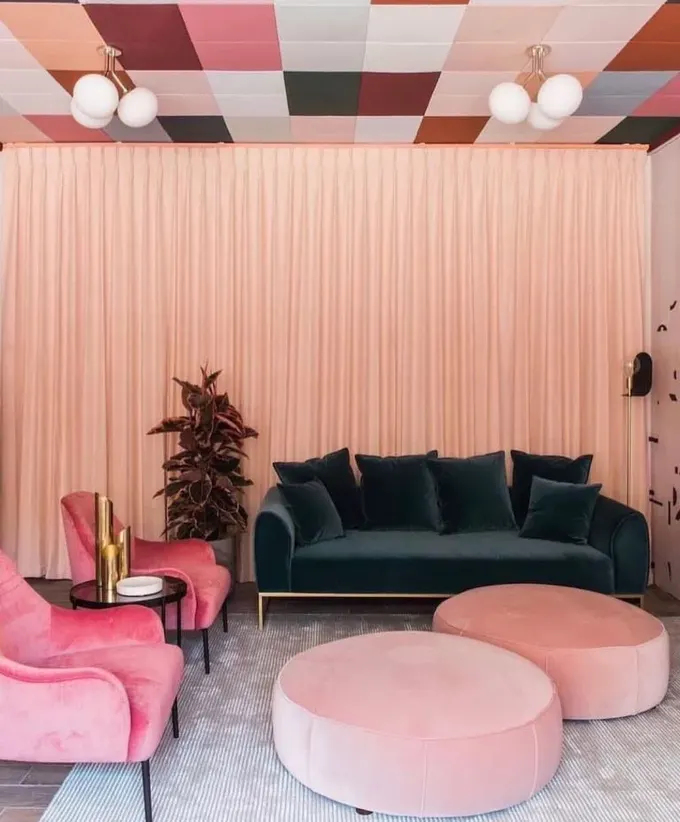 Bu oda, çeşitli pembe tonları, koyu yeşil bir koltuk ve renkli tavanıyla modern ve eğlenceli bir atmosfer sunuyor.