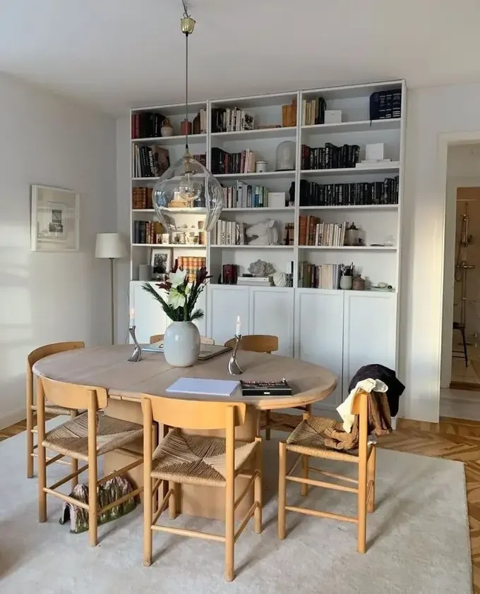 Şık modern alanda bir sıra kitaplık, açık renk mobilyalar ve avize var. İstediğiniz her şeyi yapabileceğiniz samimi bir oda.