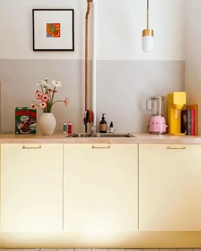 Mutfak, tereyağı sarısı dolaplar, pastel tonlarda aletler ve çiçeklerle dopamin yüklü bir alan.