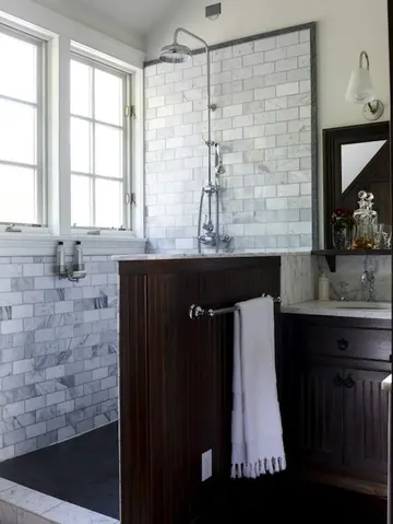 Mermer metro fayanslarla kaplı zarif banyo, koyu yarım duvar ve uyumlu vintage lavabo şıklık katıyor.