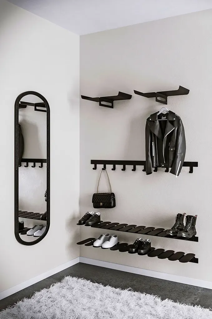 Modern giriş, uyumlu siyah metal raflar, raflar ve siyah çerçeveli bir ayna ile düzenlenmiş.