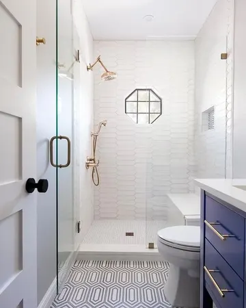 Uzun göz alıcı fayanslı duş, desenli zemin, cesur mavi lavabo, pirinç detaylar ve geometrik pencereli şık küçük banyo.